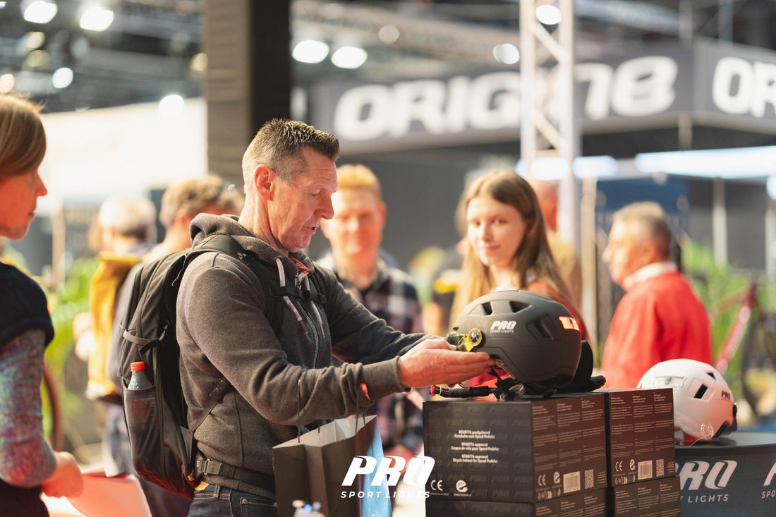 Bezoeker bekijkt een zwarte Pro Sport Lights-fietshelm met rode achterverlichting aan de stand